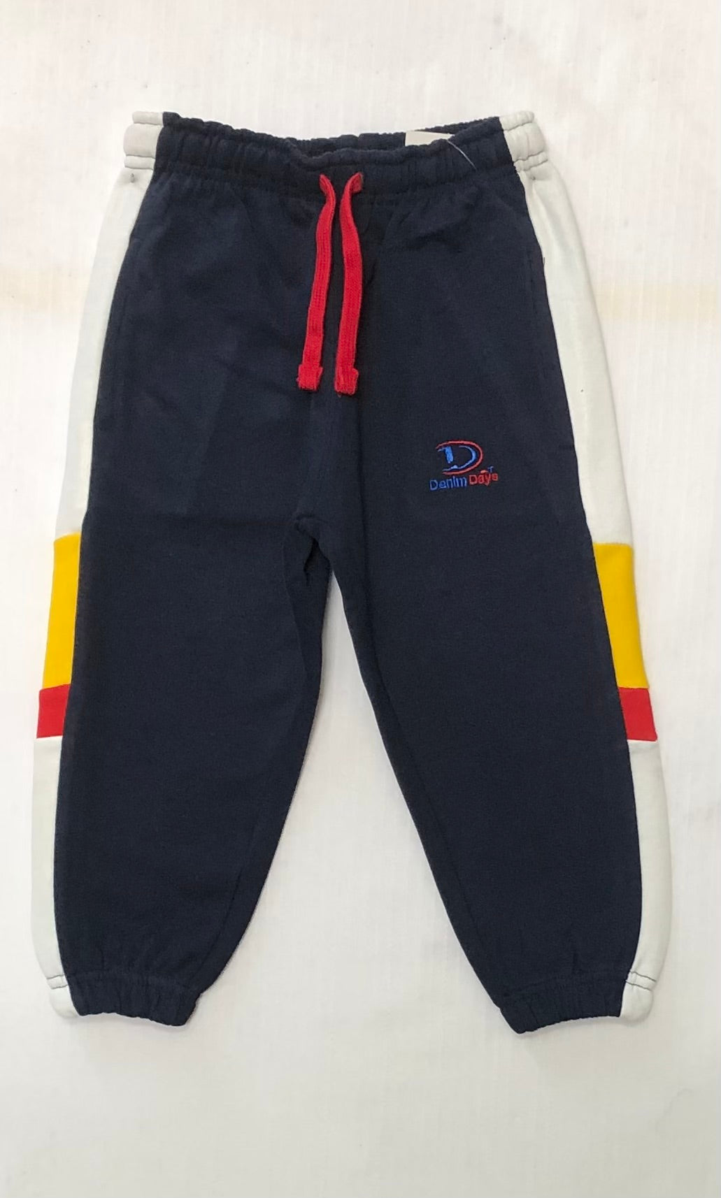 Navy blue jogger pants with colorful accents on a light gray background