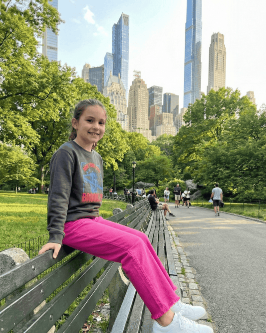 Girls Pink Jeans sitting on a bench in Central Park USA