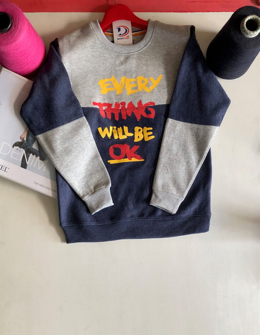 Sweatshirt with 'Everything Will Be OK' text on a white surface