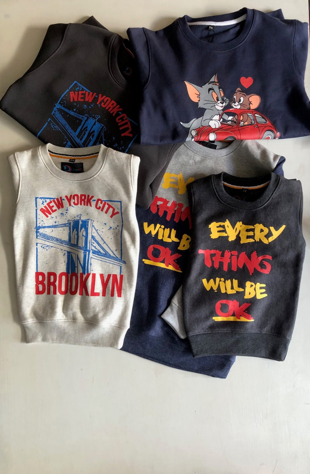 Four children's shirts with different designs on a light background